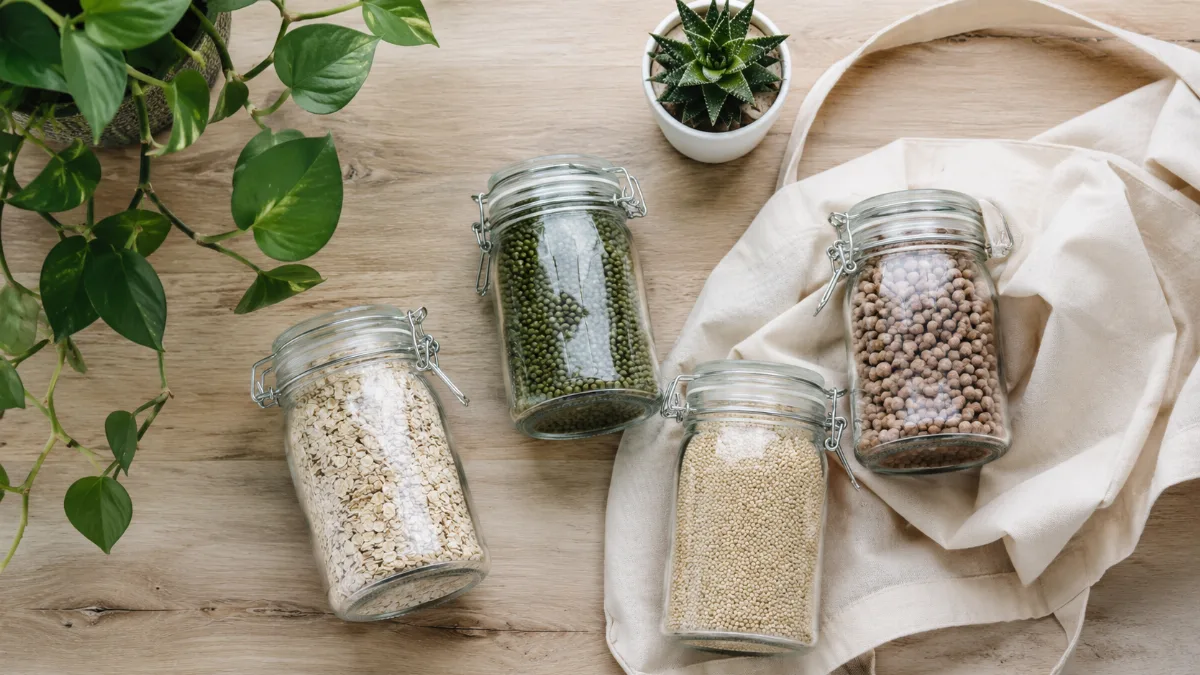 Reusable glass jars, a cloth bag and a small potted plant on a wooden surface