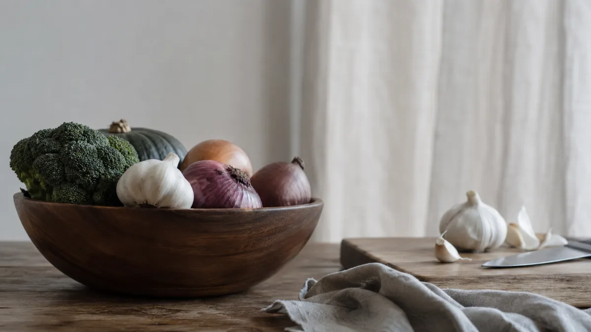 Wooden bowl of vegetables beside a chopping board