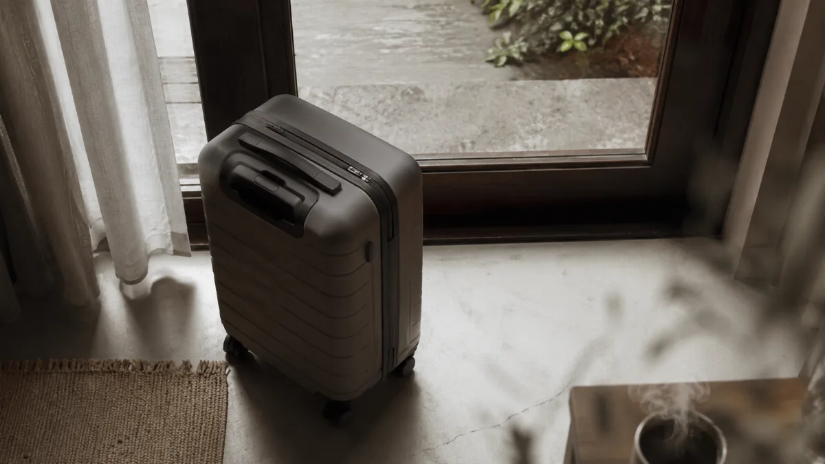 Single carry-on bag by a sunlit doorway